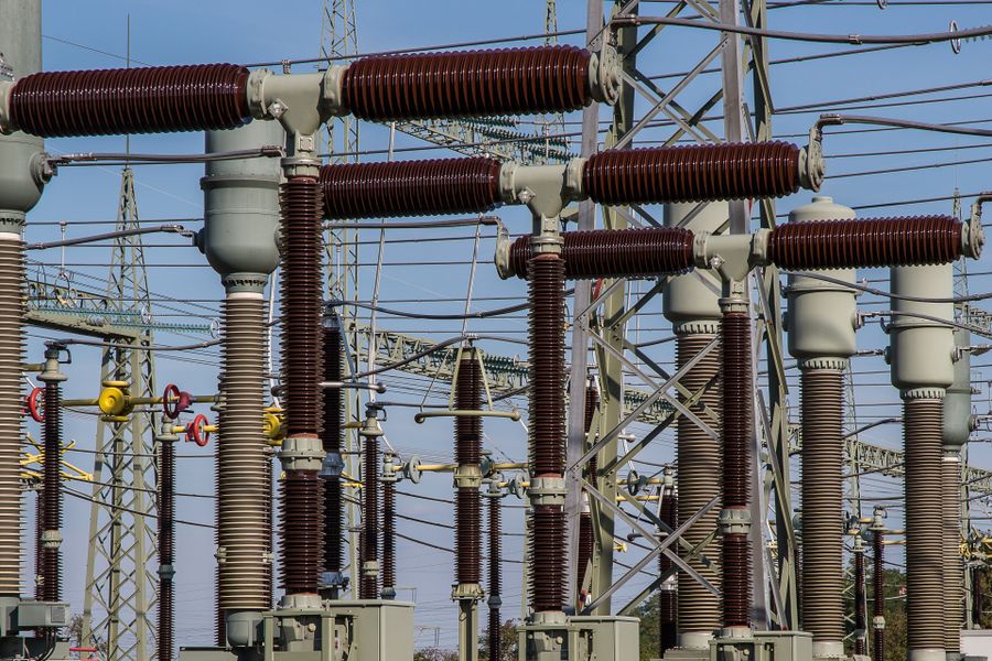 High-voltage substation insulators and busbars against a blue sky